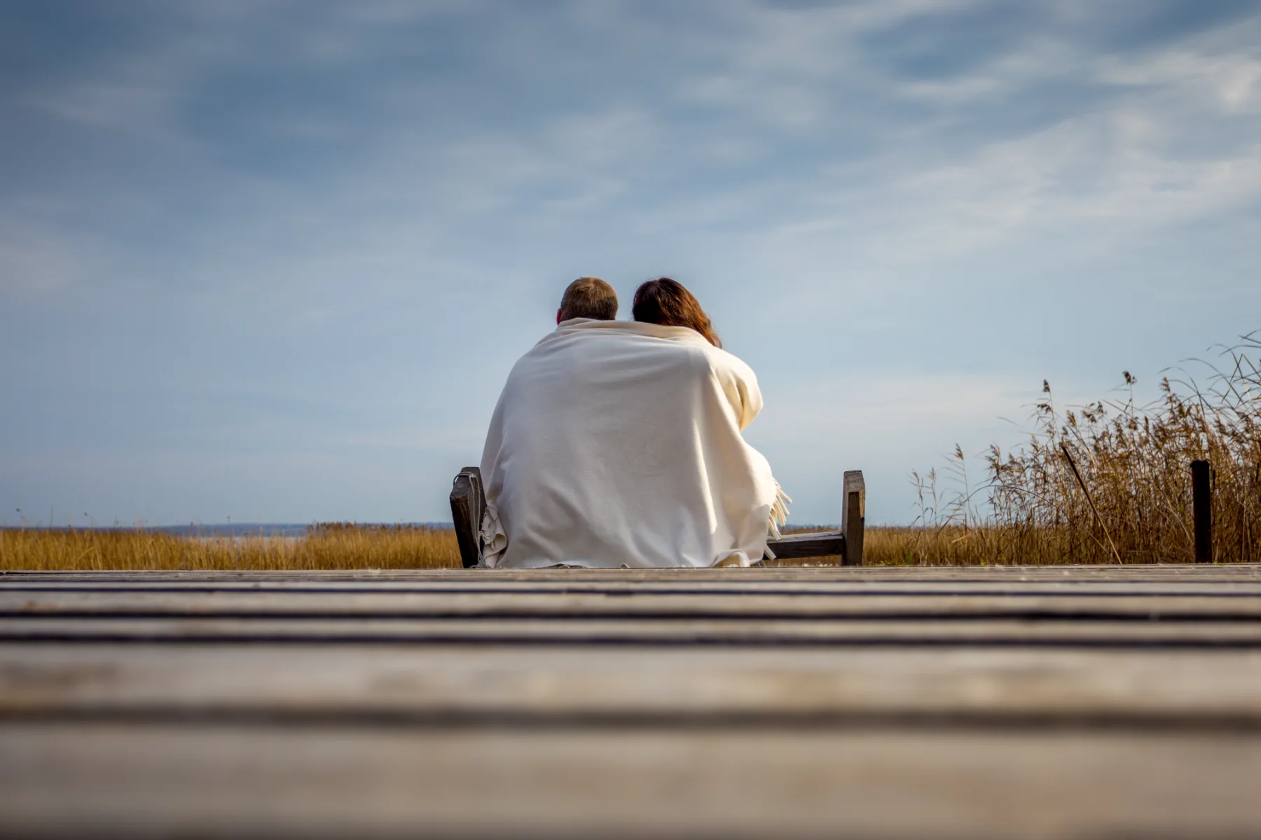 Couple enveloppé dans une couverture face à l'horizon – se soutenir pendant un arrêt de travail