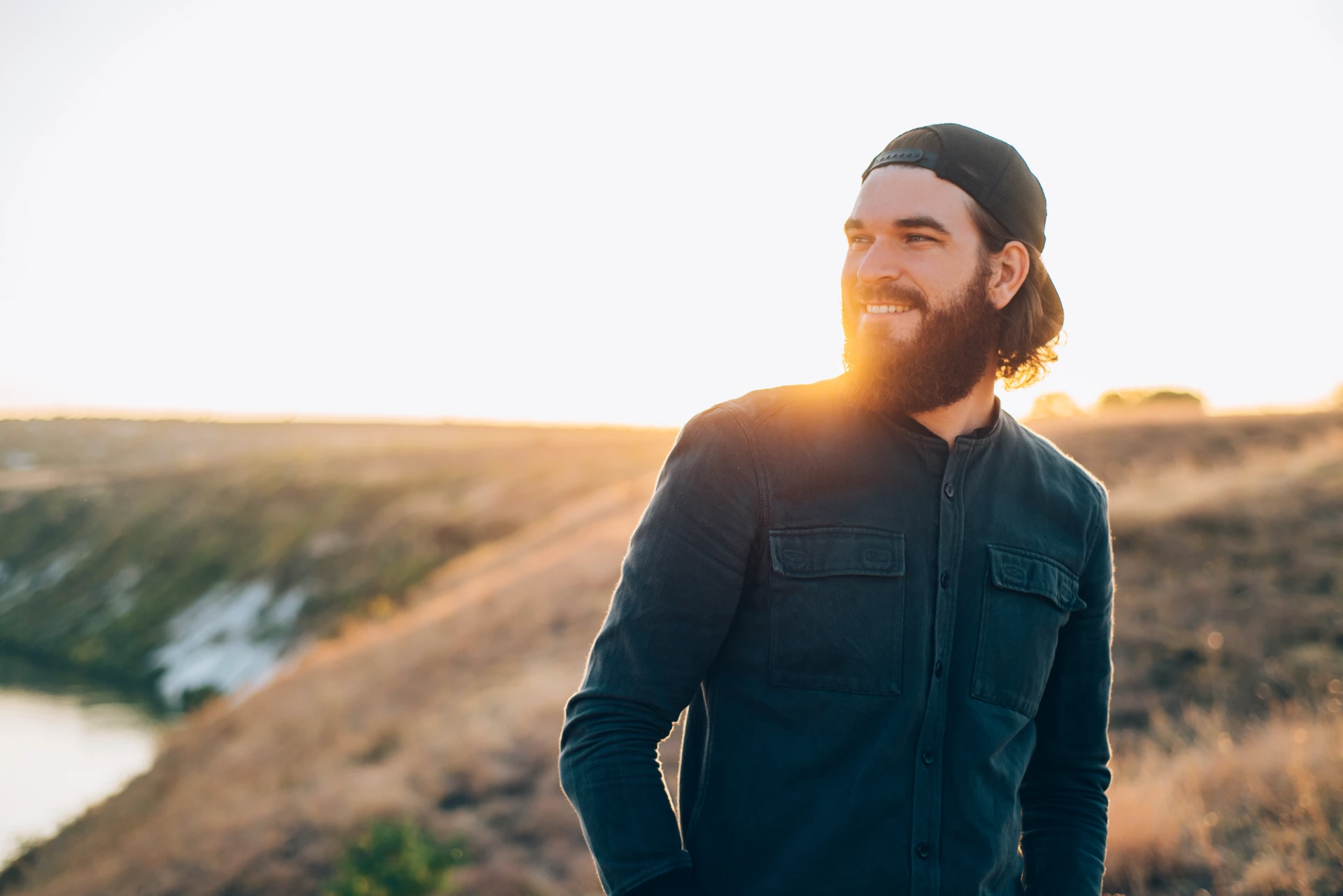 Homme souriant dans un champ au lever du jour, symbole d'un nouveau départ après une faillite personnelle