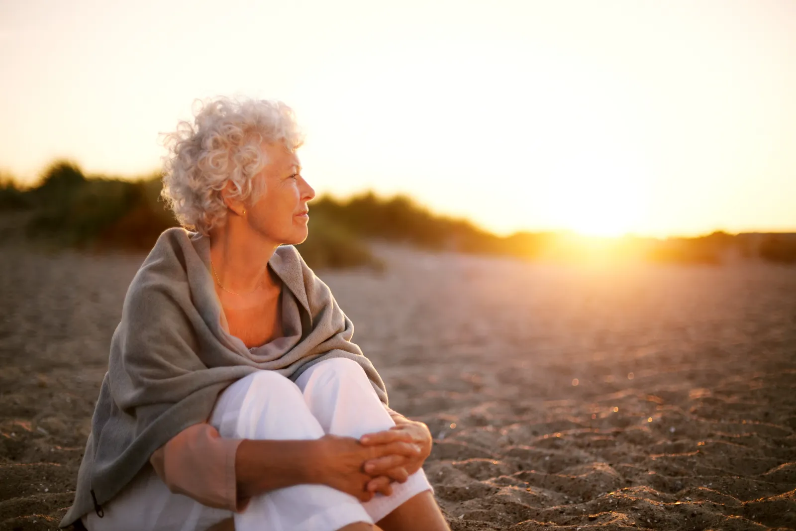 Femme aînée sereine sur la plage au coucher du soleil – succession insolvable, des options pour les héritiers